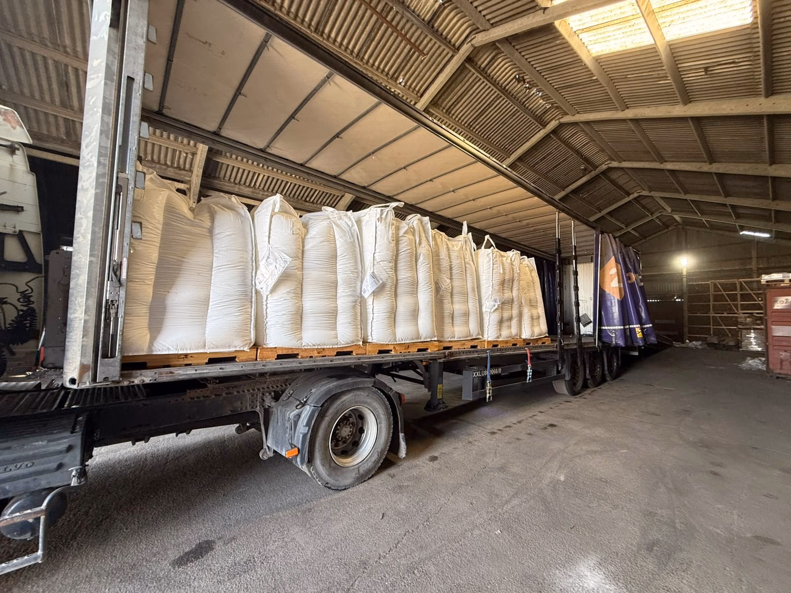 Bulk bags loaded along a flatbed trailer parked inside the warehouse