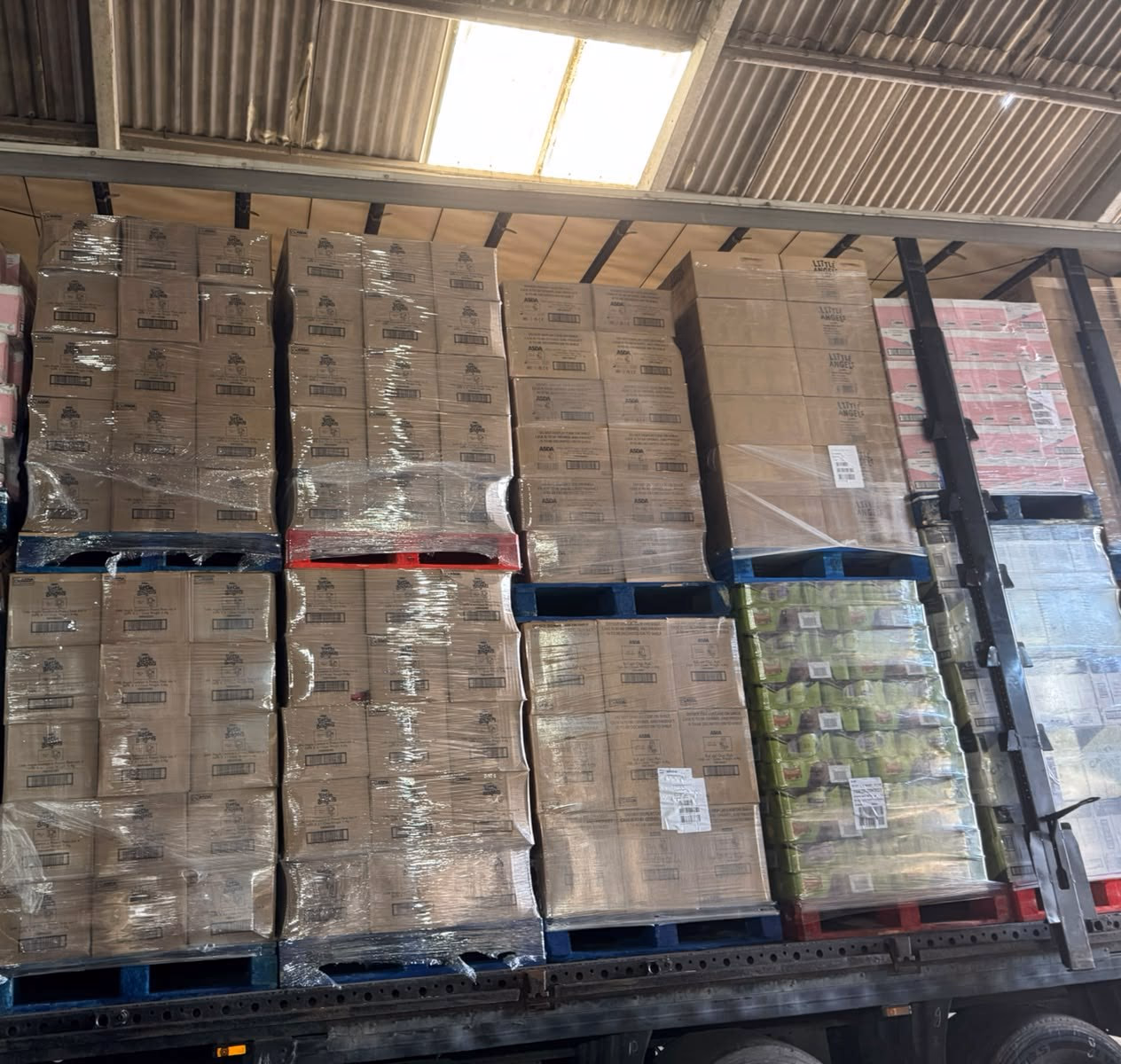 A curtain-sided trailer loaded with two tiers of wrapped pallets
