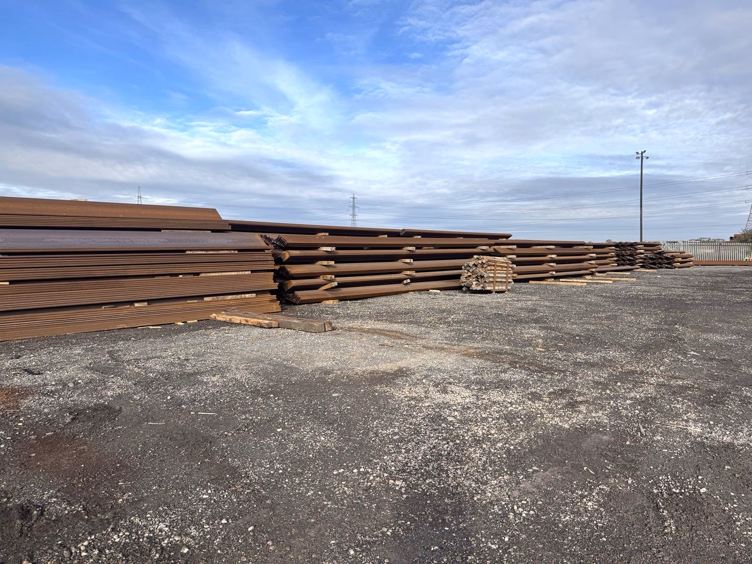 Rows of steel sheet piles stacked in organised outdoor storage