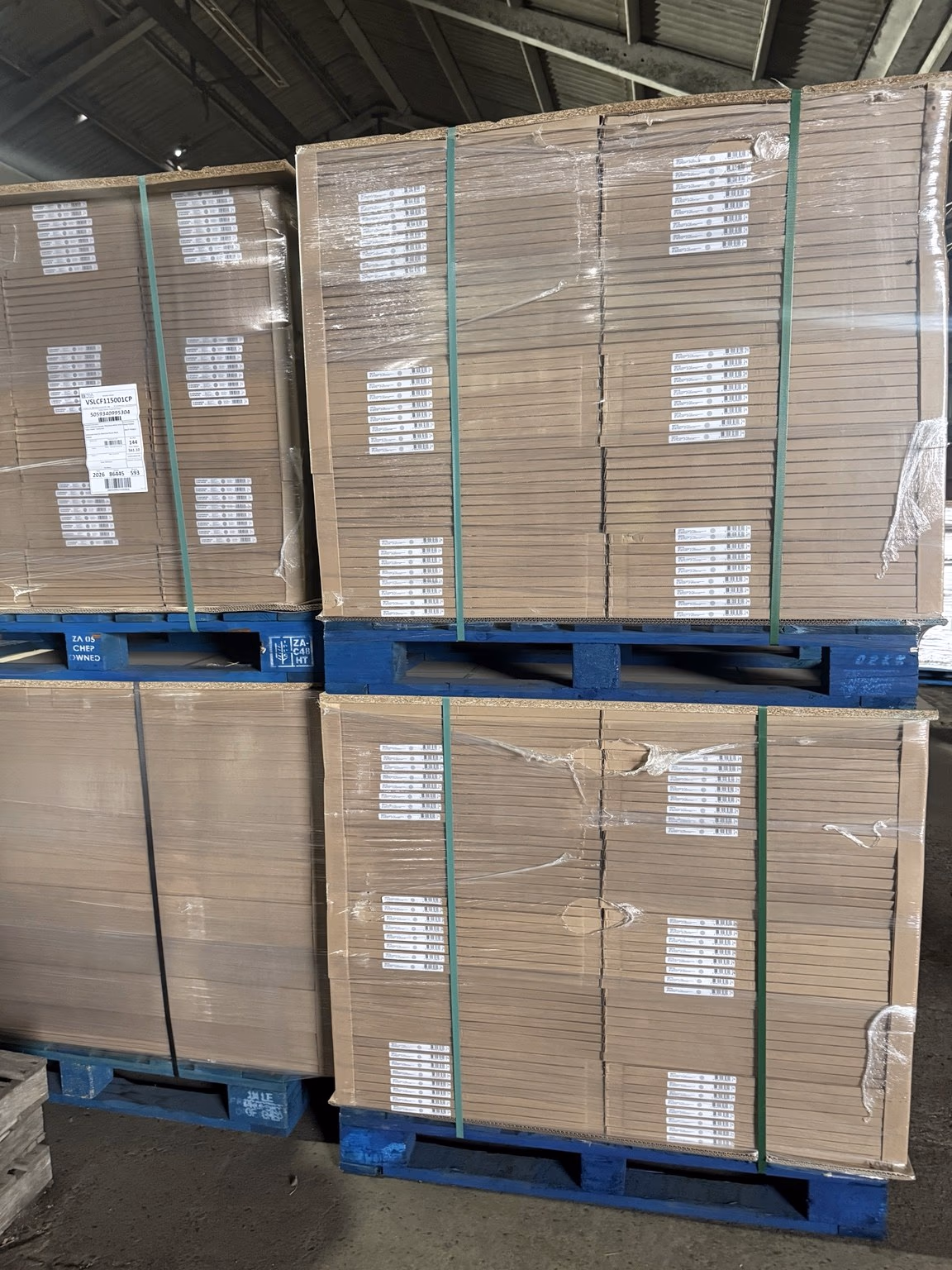 Strapped and wrapped pallets of boxed goods stored two high on blue pallets