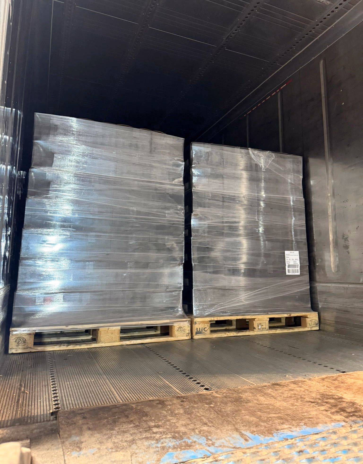 Two neatly stacked and stretch-wrapped pallets standing square inside a trailer